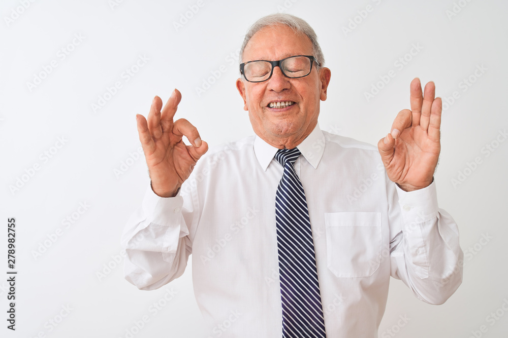 Senior grey-haired businessman wearing tie and glasses over isolated white background relax and smiling with eyes closed doing meditation gesture with fingers. Yoga concept. Senior grey-haired businessman wearing tie and glasses over isolated white background relax and smiling with eyes closed doing meditation gesture with fingers. Yoga concept.