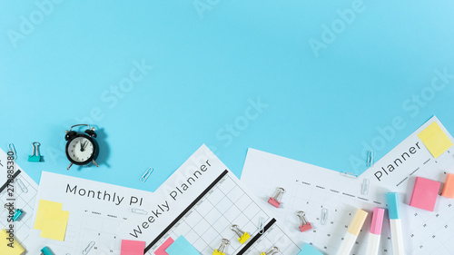 Alarm clock, stationery and planner on blue pastel background
