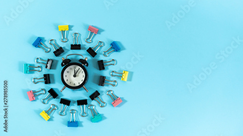 Alarm clock and stationery clip on blue pastel background