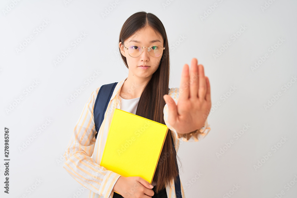 Chinese student woman wearing glasses backpack book over isolated white background with open hand doing stop sign with serious and confident expression, defense gesture Chinese student woman wearing glasses backpack book over isolated white background with open hand doing stop sign with serious and confident expression, defense gesture