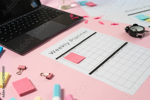 Laptop, stationery and planner on pink pastel background
