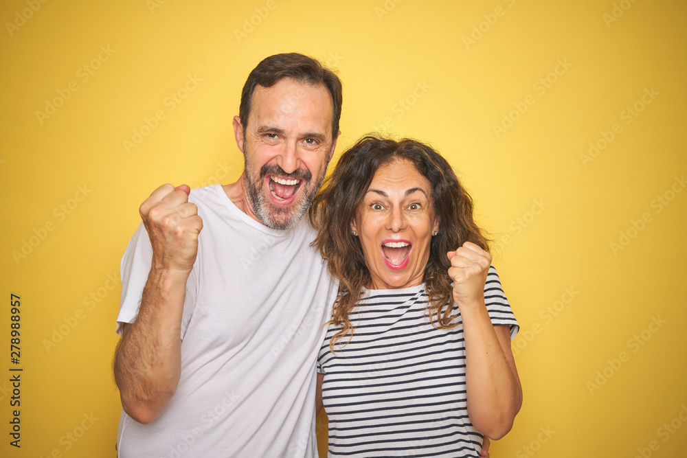Beautiful middle age couple together standing over isolated yellow background screaming proud and celebrating victory and success very excited, cheering emotion Beautiful middle age couple together standing over isolated yellow background screaming proud and celebrating victory and success very excited, cheering emotion