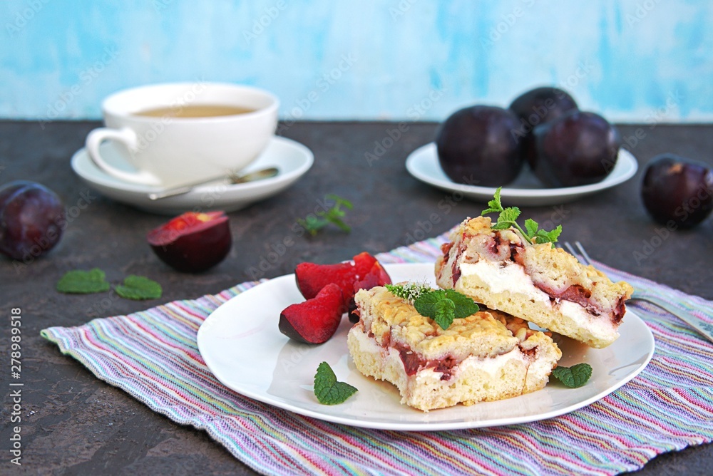 Sliced shortbread cake with curd cream and plum on a white plate. Sweet cakes. Harvest plums.