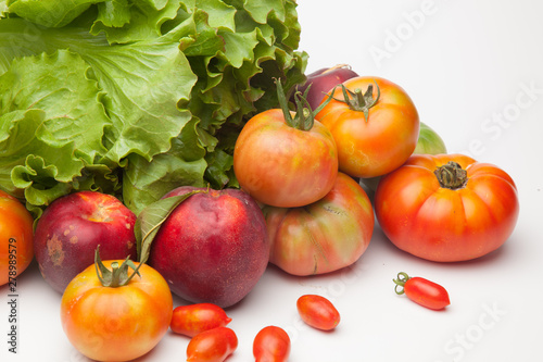 Lechuga verde y distintas frutas, tomates, cherri y de los otros, nectarinas todo sobre fondo blanco