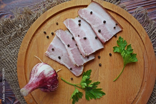 Delicious smoked bacon with spices,herbs and garlic on wooden background.
