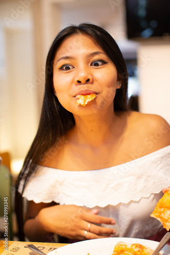 Young asiatic woman eating pizza happy
