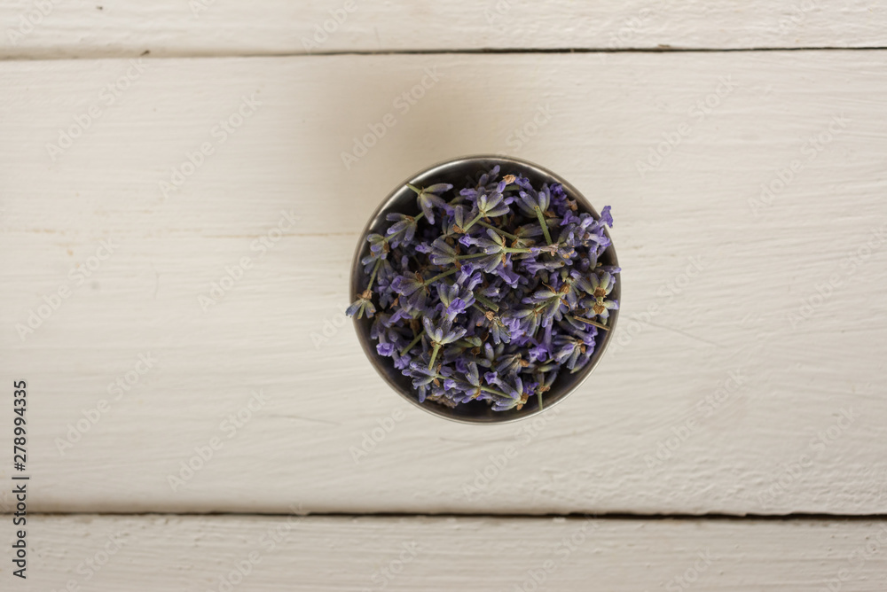 Closeup photo on top of a wooden background with a small bowl with fragrant lavender.