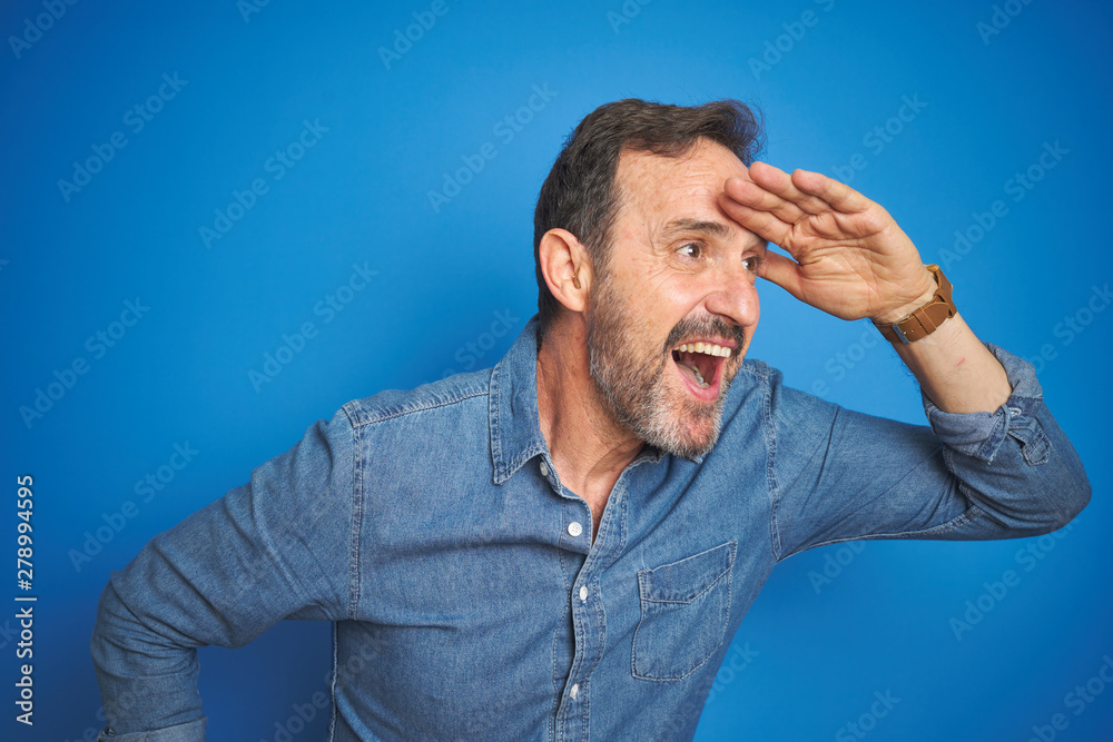 Handsome middle age senior man with grey hair over isolated blue background very happy and smiling looking far away with hand over head. Searching concept. Handsome middle age senior man with grey hair over isolated blue background very happy and smiling looking far away with hand over head. Searching concept.