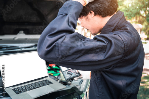 Mechanic Using Laptop While Examining Car Engine, pointing in blank screen