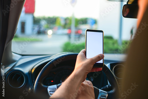 Hand holding phone white screen display in car. Man driver using smart phone in car.