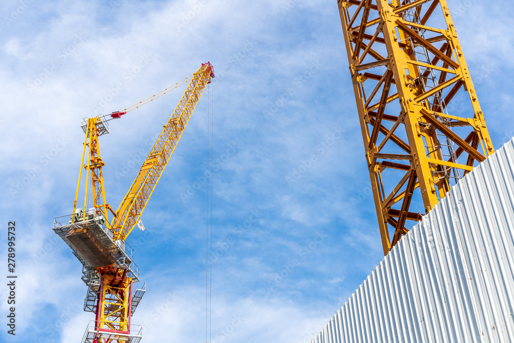 Crane working in construction site with cloud and blue sky in background. Crane working in construction site with cloud and blue sky in background.