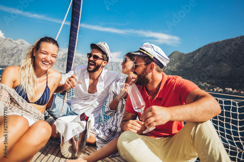 Smiling friends sitting on sailboat deck and having fun.Vacation, travel, sea, friendship and people concept