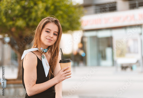 Beautiful young girl drinks coffee in the street