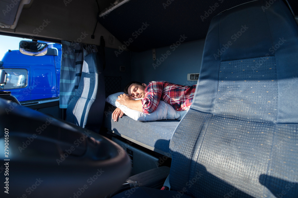 Truck driver sleeping on bed inside truck cabin interior. Trucker