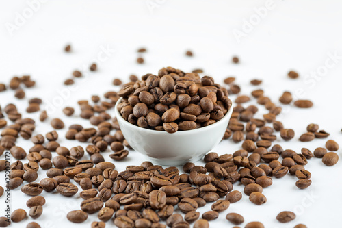 Roasted coffee beans in ceramic bowl on white  close-up