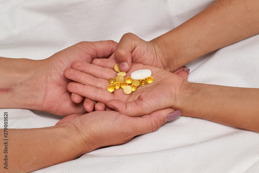 Tablets or capsules in your hand, palm, or fingers. Medicinal prescription female hands pass pills to a sick child, light background Tablets or capsules in your hand, palm, or fingers. Medicinal prescription female hands pass pills to a sick child, light background