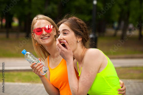 Two girlfriends walking on summer park, outdoors