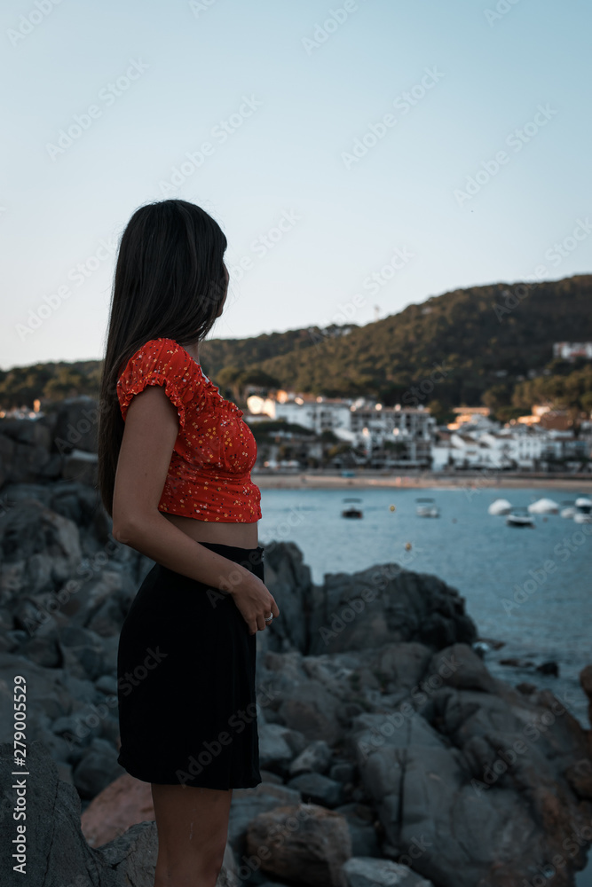 Modelo femenina mirando hacia un pueblo en la costa mediterránea 
