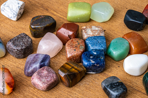 Collection of different colored polished gemstones an jewels luxury on wooden underground photo