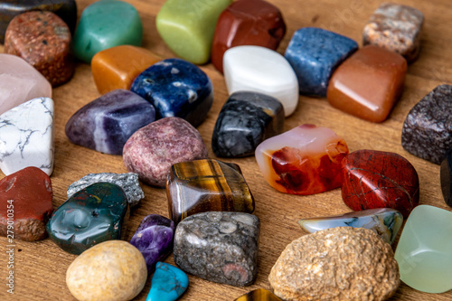 Collection of different colored polished gemstones an jewels on wooden underground photo