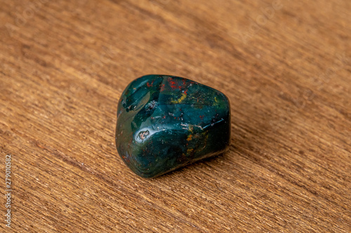 Indian Achat deep green gemstone with red and yellow structures all over on wooden undergroundit