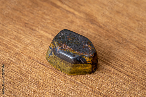 Tiger iron gemstone precious gem with shiny surface yellow and grey on wood