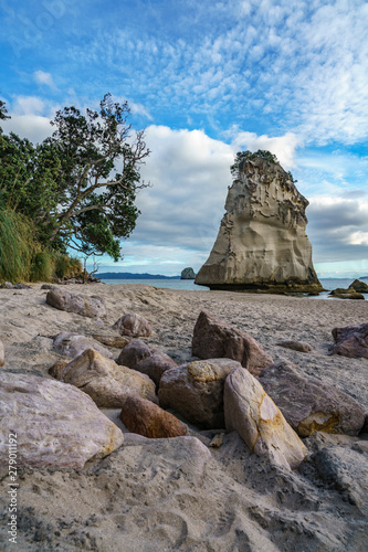 sandstone rock monolith behind stones in the sand at cathedral cove, new zealand 4