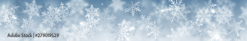 Christmas banner of complex blurred and clear snowflakes in white colors on light blue background. With horizontal repetition