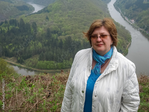 Mature woman in a light jacket and glasses resting in the Park