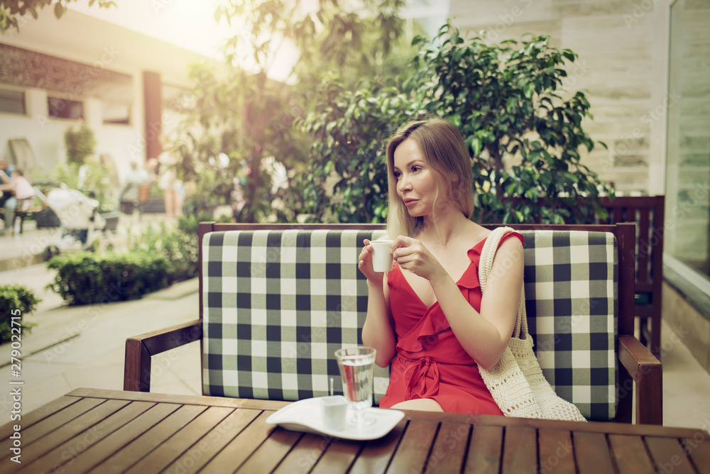 Young woman enjoying Turkish coffee in street cafe.