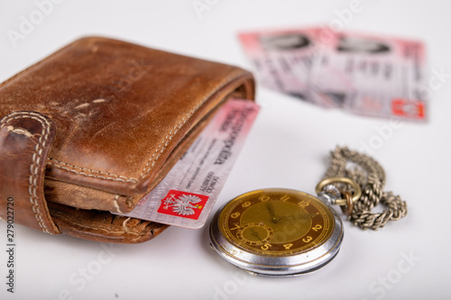 Leather wallet and an old watch on a white table. Personal documents in leather cover.