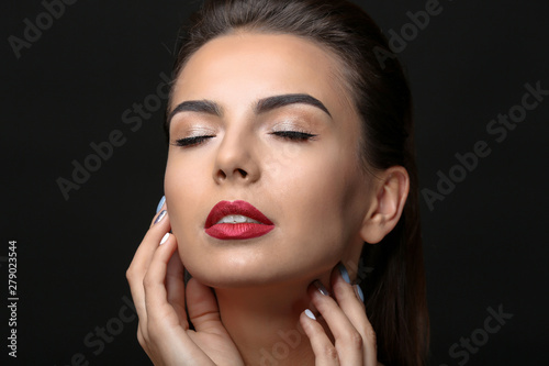 Young woman with beautiful eyebrows on black background