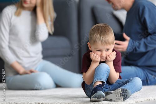 Sad little boy in room with quarreling parents. Family conflict
