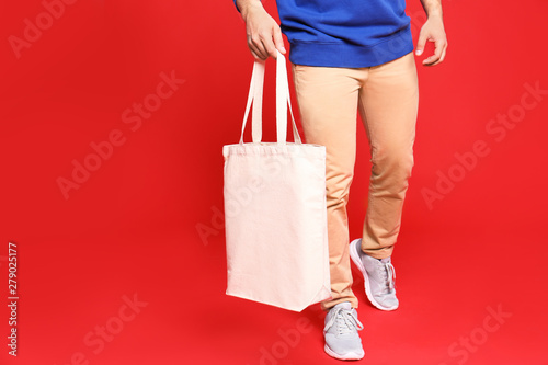 Young man with eco bag on red background, closeup