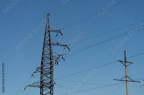 High voltage lines and power pylons in the industrial area on a Sunny day with a clear blue sky.
