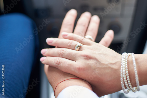 Newlyweds in the car show hands with wedding rings on the fingers.