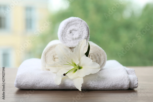 Pile of fresh towels and flower on table against blurred background