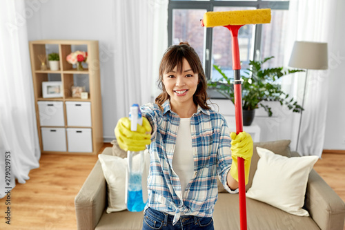 cleaning, housework and housekeeping concept - happy asian woman or housewife in gloves with window cleaner and sponge mop at home