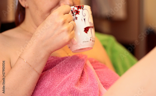 Woman with a cup of coffee in pink towel