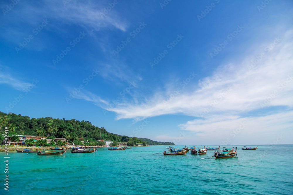 Traditional Thai fishing boats wrapped with colored ribbons. Against the backdrop of a tropical island