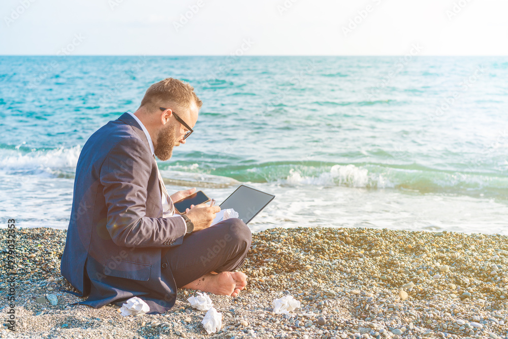 Businessman working with computer on the beach