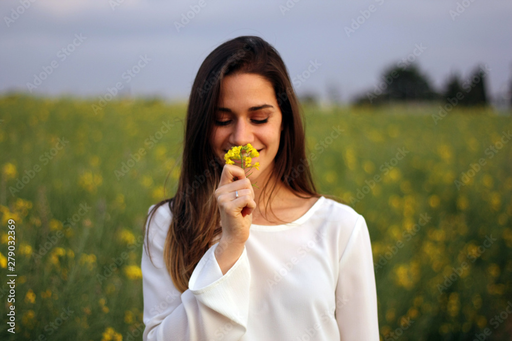 Women smelling yellow flower in yellow flowers field Women smelling yellow flower in yellow flowers field