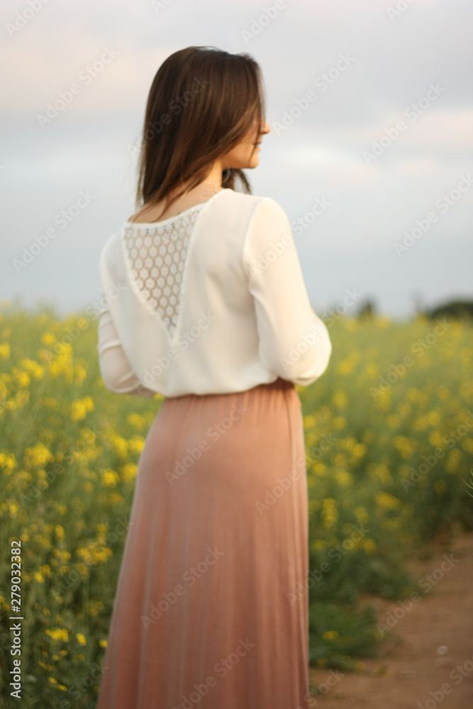 Beautiful woman on yellow flowers field with dark cloudy sky Beautiful woman on yellow flowers field with dark cloudy sky