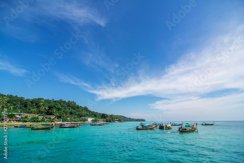 Traditional Thai fishing boats wrapped with colored ribbons. Against the backdrop of a tropical island © Kate