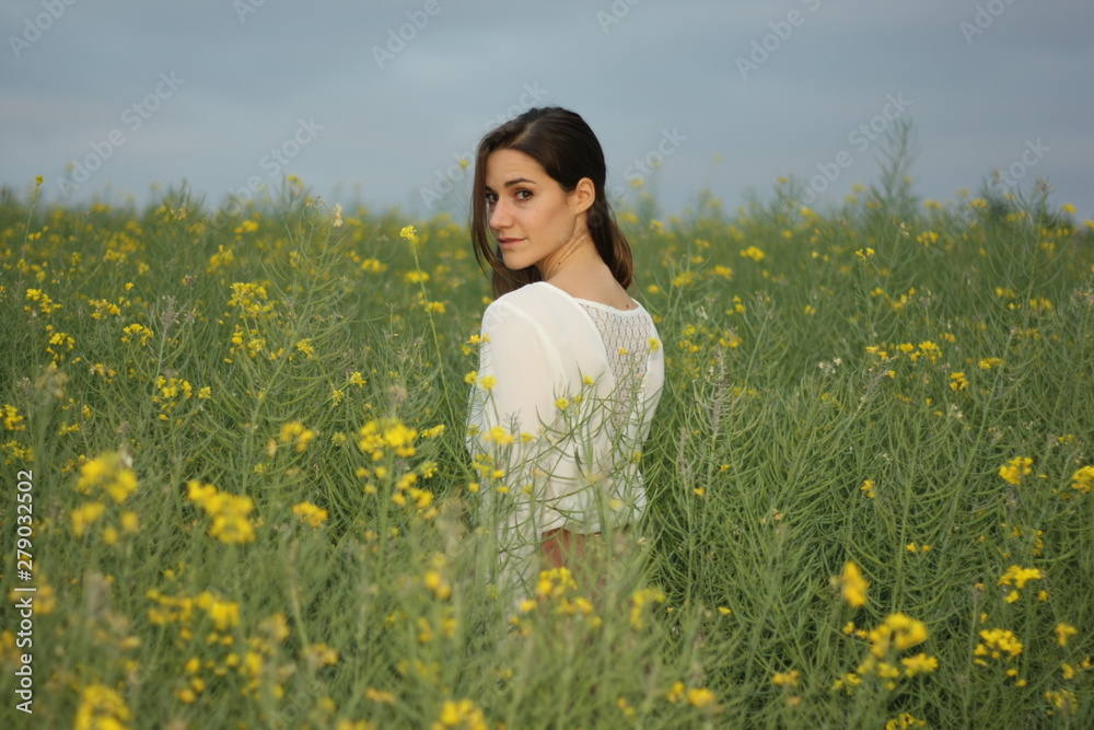 Beautiful woman on yellow flowers field with dark cloudy sky Beautiful woman on yellow flowers field with dark cloudy sky