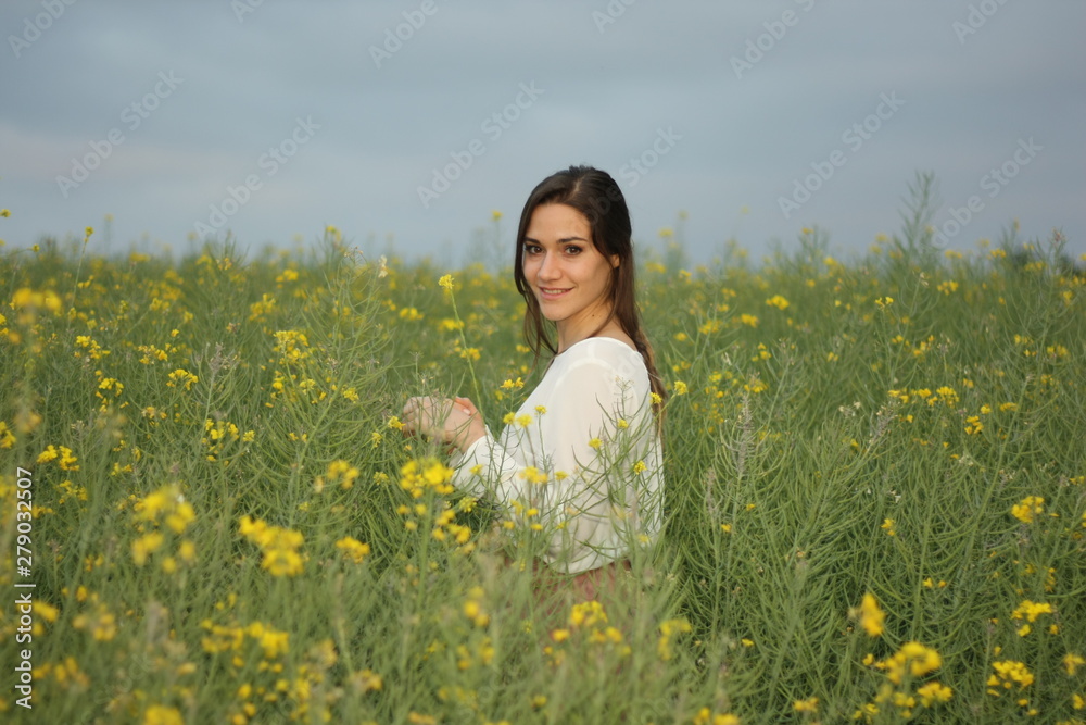 Beautiful woman on yellow flowers field with dark cloudy sky Beautiful woman on yellow flowers field with dark cloudy sky