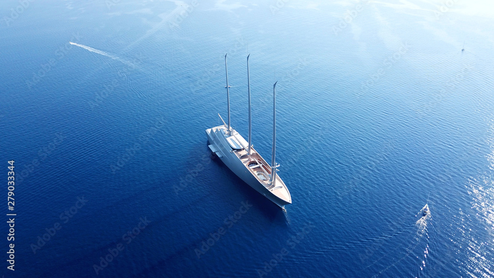 Fototapeta premium Aerial photo of sail boat cruising in deep blue waters of Santorini island, Cyclades, Aegean, Greece
