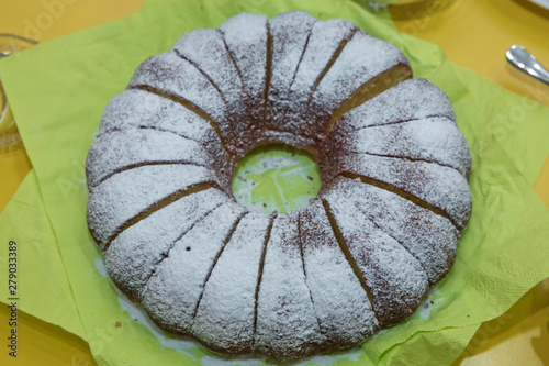 homemade bundt cake with icing sugar. Hamemade bundt cake with white flour on the green background. photo