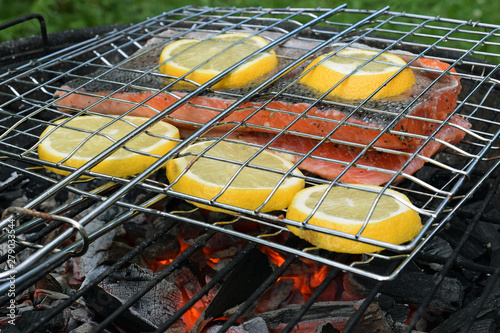 Φωτογραφία Grilling salmon with lemon slices on charcoal grill with gridiron