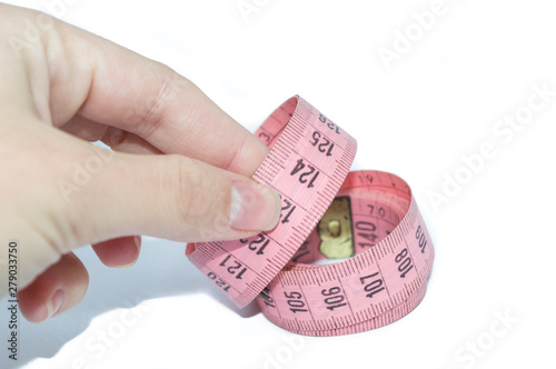 hand holding pink measuring tape, to control body measurements or use of seamstresses, isolated on white background